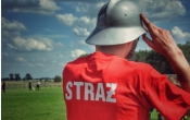 Strazak w czerwonej koszulce z napisem straz i szarym helmie