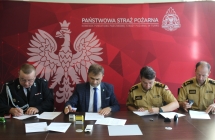 4 mezczyzn siedzi przy biurku i podpisuje dokumenty