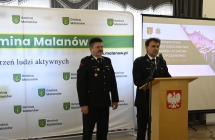 dwoch strazakow na tle scianki z napisem gmina Malanow