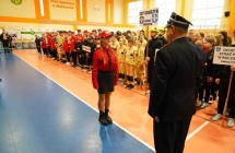 dziewczynka w czerwonym mundurze stoi przed strażakiem w mundurze