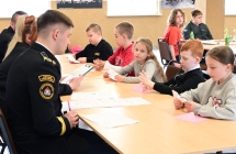 grupa osob siedzaca przy stole, na pierwszym palnie mezczyzna w mundurze strazackim