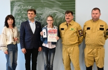 grupa stojacych osób w tym dwie osoby w strażackich mundurach