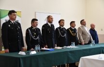 grupa stojacych osob przy zielonym stole